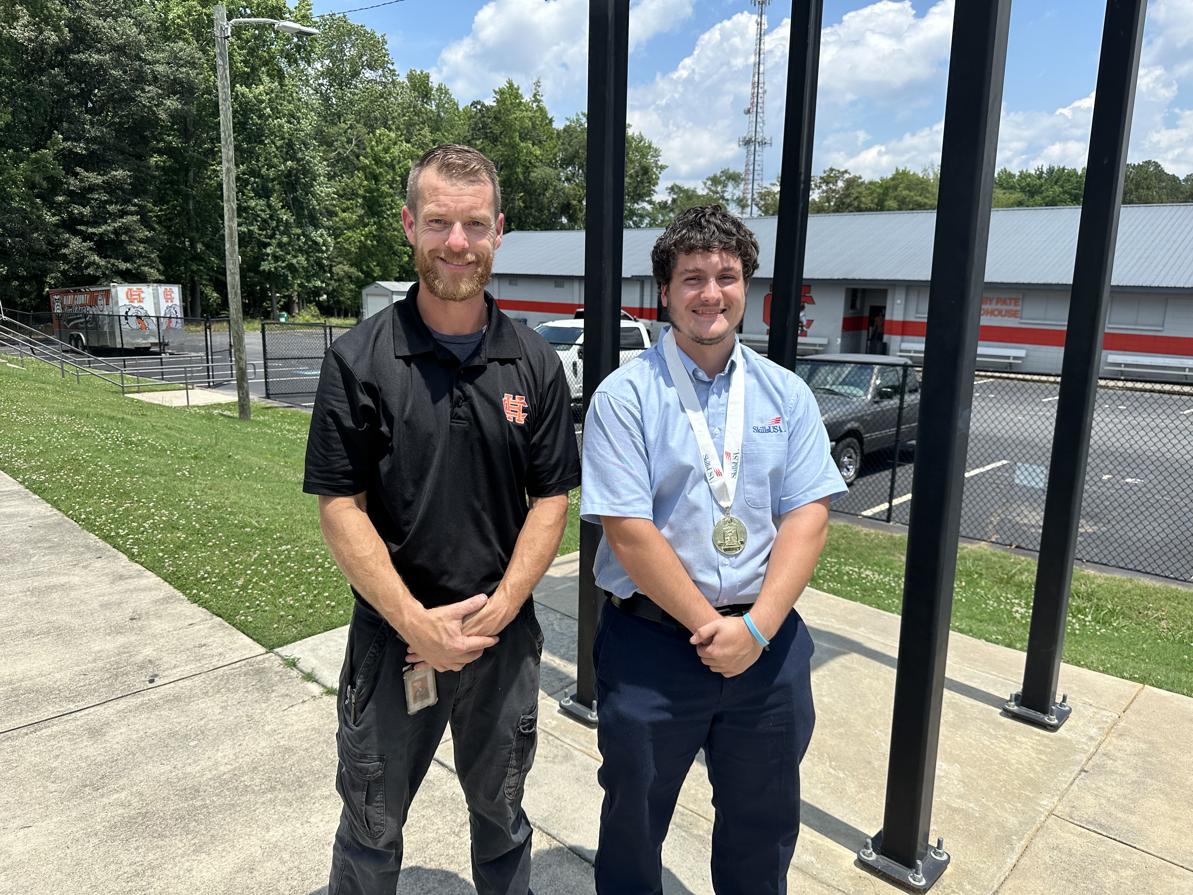 Jimmy Reynolds (right) poses for a photo with Marine Engine Technology instructor Tyler Floyd (left) after ringing the Victory Bell at Hart County High School following his National Championship win. Photo by Grayson Williams. 
