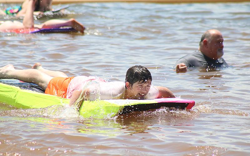 Sunshots by Grayson Williams — Carter Reed navigates his paddle-board style boat past band director Alan Tolbert, right, who officiated the event from the water.