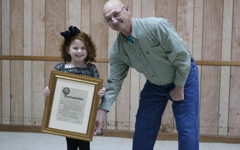 Sunshot by Grayson Williams - Outgoing Bowersville Mayor Jim Jordan, right, poses for a photo with Lainey Moon. Jordan proclaimed Aug. 25 as Lainey Jo Moon Day at a meeting on Dec. 19 after Moon won a Cabbage Patch Doll look-alike contest.