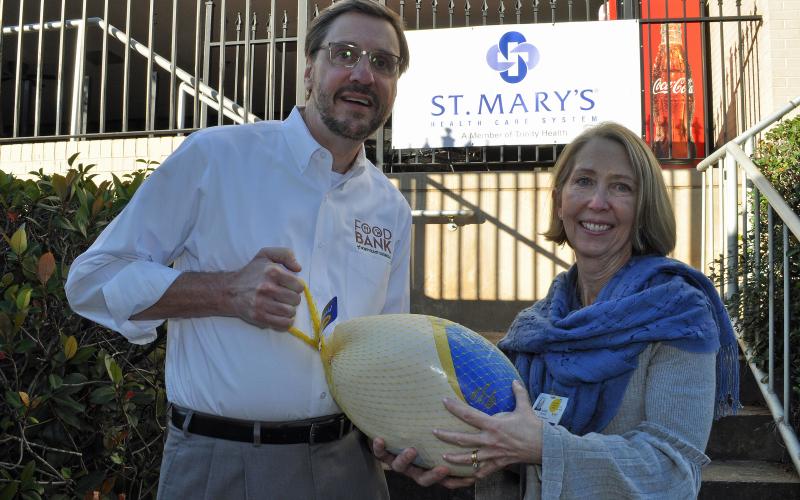 Photo submitted — Food Bank of Northeast Georgia Executive Director Chuck Toney, left, accepts a turkey from St. Mary’s Vice President of Mission Services Julie Carter.