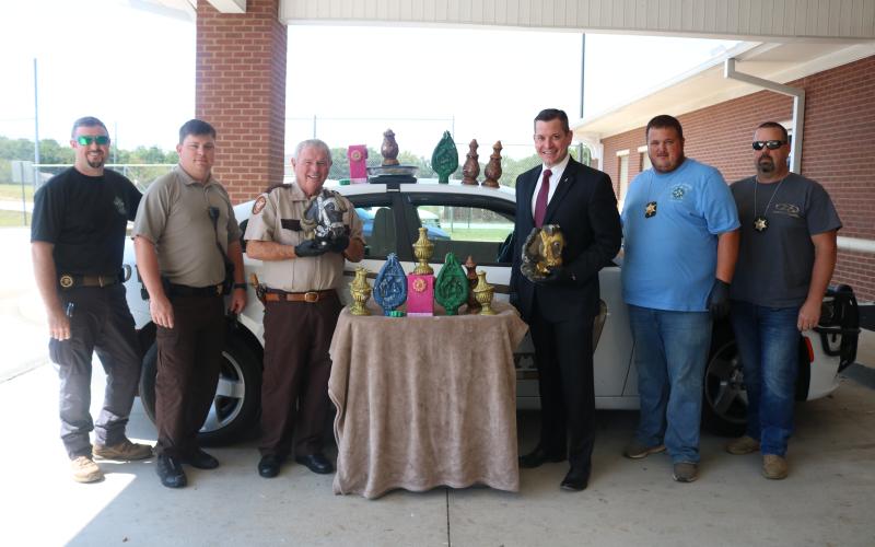 Sunshot from file — Hart County Sheriff Mike Cleveland, to the left of the table, and District Attorney Parks White, to the right of the table, pose for a photo earlier this year with deputies and a large amount of methamphetamine that had been formed in the shape of candles.