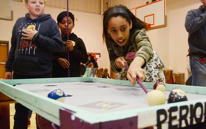 Sunshot by Michael Hall - Fifth-grader Deanna Howell lines up a shot on the Periodic Pool Table while Landry Carter and José Mendez look on on Jan. 31 at South Hart Elementary.