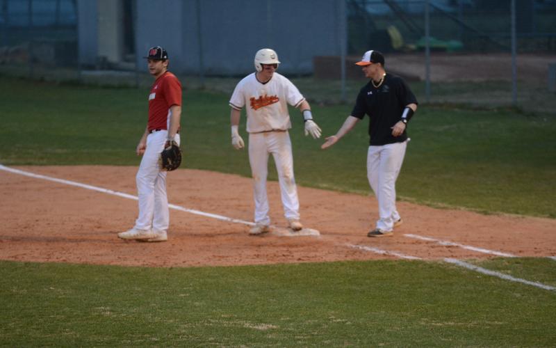 Luke Lee, left, is congratulated by coach Hunter Barton, at first base after Lee’s line drive that drove in a run to take the lead against Morgan County on Monday at Saye Field.