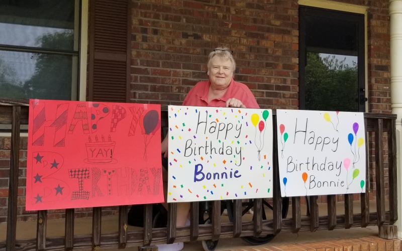 Sunshot by Kerri Pruitt — Bonnie Granville poses for a photo with signs made for her birthday parade by friends, former colleagues and students.