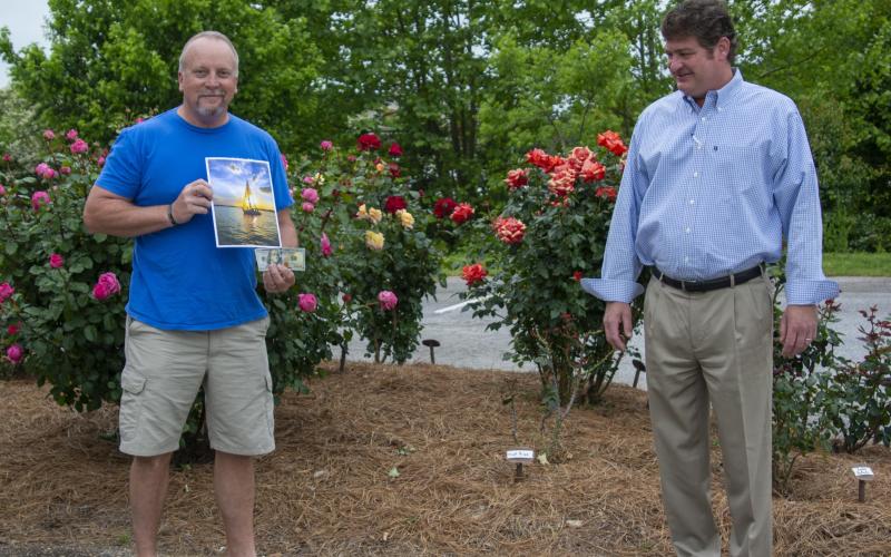 Photo by Kimberly Brown — Spring Lake Living cover contest winner Douglas Whiddon, left, of Cleveland, receives his $100 prize from Alan NeSmith, publisher of CNI Newspapers’ Lake Living. Whiddon is holding his photo of a sailboat in the sunset on Lake Lanier, which will be featured on the spring edition of Lake Living, on newsstands now.