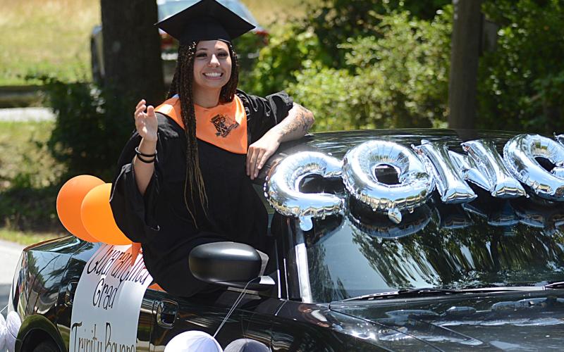 Trinity Bowers hangs out of a Dodge Charger and waves to the crowd as the parade passes.