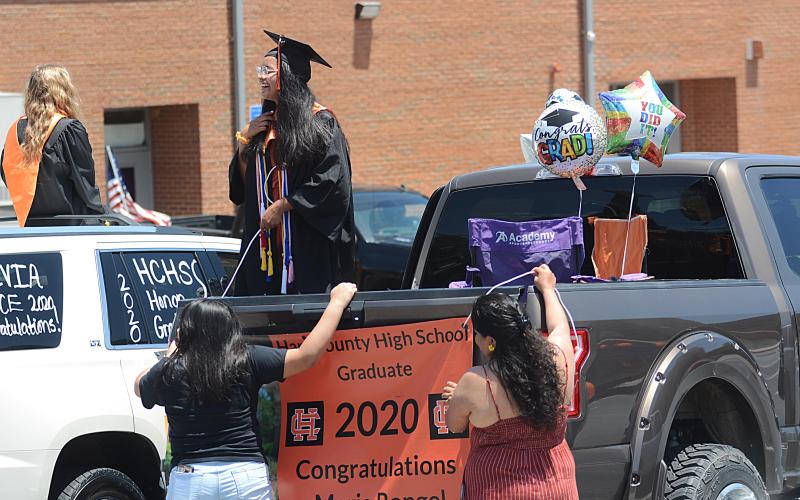 Sunshots by Michael Hall Maria Rangel talks with another graduate as her family helps her hang a banner from the back of a truck prior to the Parade of Graduates on May 23 in Hartwell.