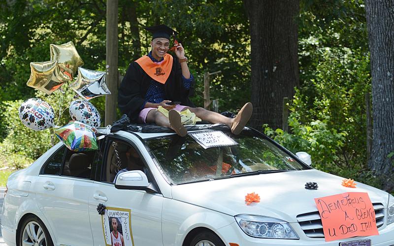 Graduate Demetrius Glenn rides atop a Mercedes in the parade down Campbell Drive.