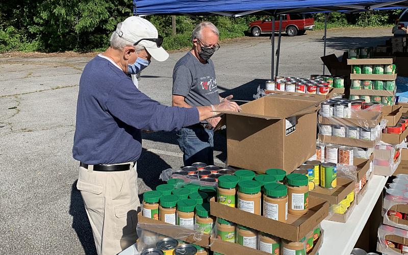 Photo submitted — Hartwell Rotary Club members Jerry Dawson, left, and Earl Johnson, right, help with a food giveaway by Hart Partners on May 6 at the Adult Learning Center on Benson Street in Hartwell.