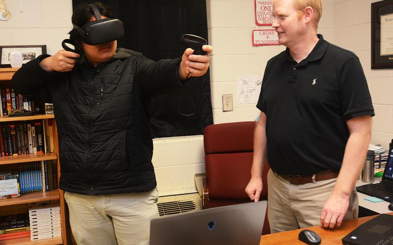 Sunshot by Michael Hall — Hart County High School’s STAR student, Sean Pak, left, and STAR teacher, Rob Elliot, right, demonstrate a virtual reality game in February that they had hands in creating. It is one of many stories from the Hart County Charter System covered by The Sun.