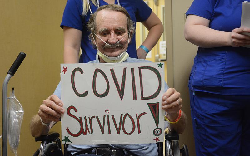 Sunshot by Michael Hall — Richard Frady holds a sign identifying himself as a COVID-19 survivor.