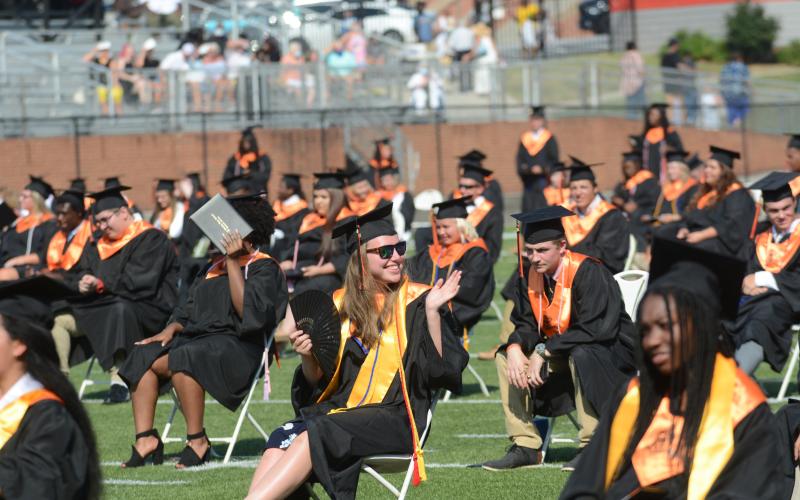 Sunshots by Michael Hall Kaylee Todd, center, waves at family in the audience while fanning herself as the morning sun grew hotter Saturday during Hart County High School’s graduation ceremony.