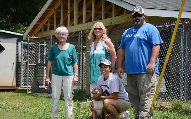 Sunshot by Michael Hall — Hart County Humane Society volunteers Judy Peebles, left, Pam McGovern, middle, Melanie Wood, kneeling with Mama Jenny, and Chad Wiloughby of Rock Solid Builders pose for a photo in front of the new covered outdoor run area for dogs at the J. Robert Mauldin Animal Sanctuary.