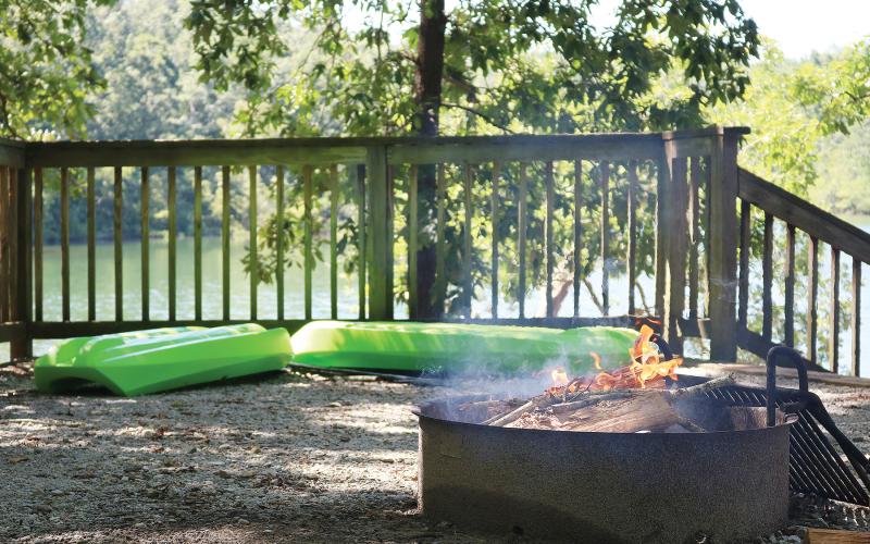 Sunshot by Grayson Williams — A fire burns in a fire pit as kayaks wait to hit the water at a Hartwell Lakeside campsite recently.