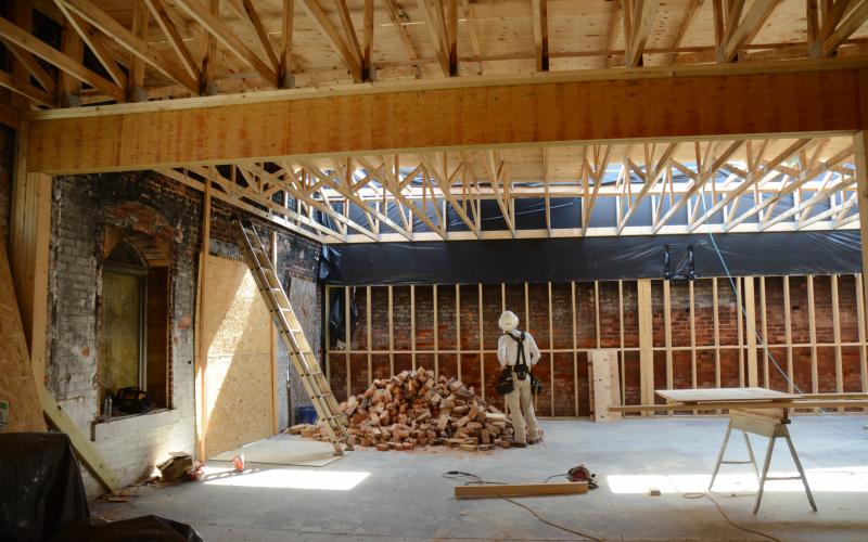 Sunshot by Michael Hall — A construction worker with J. Davis Construction stands inside the ongoing renovations at Little Japan in downtown Hartwell a year after the restaurant burned.