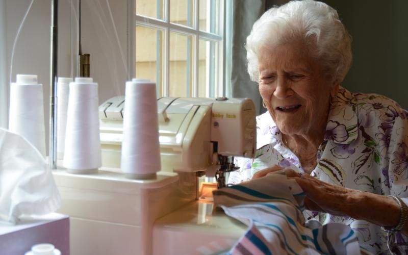 Sunshot by Michael Hall - Doris Mahannah works on a onsie for a newborn at her home in Hart County recently. Mahannah is 104 years old and contributes regularly to Tiny Stitches.