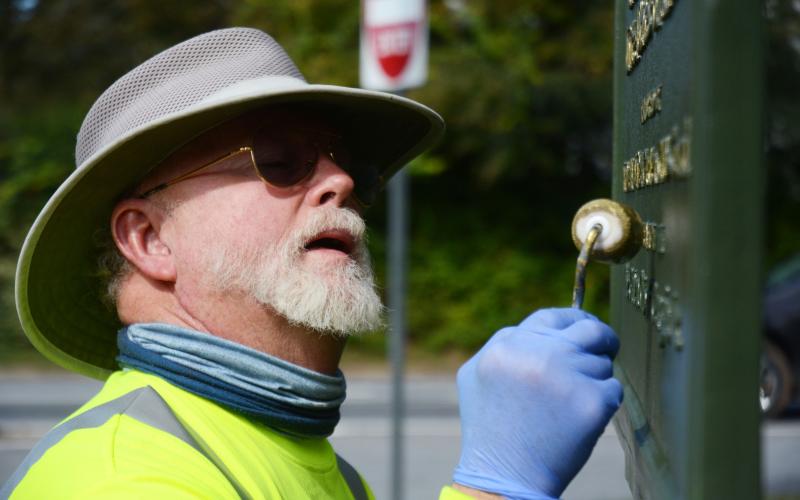 Tom Stelling carefully dabs gold paint on the lettering of the Blue Star Memorial at the corner of Athens and Howell streets in Hartwell on Oct. 25.