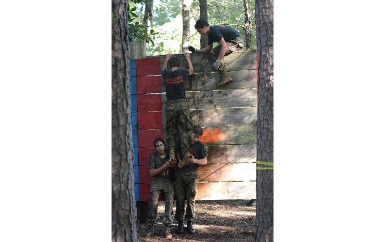 Vincent Perez and Andrew Brezeale boost Cole Risner over the 10 foot wall to finish the obstacle course.