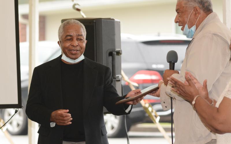 Sunshot by Michael Hall - Nathaniel Clark, left, accepts a plaque from Larry Fouch, right, during the ceremony unveiling a historical marker at the site of the former Hart County Training School on Richardson Street in Hartwell.