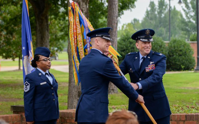 Col. Seth Graham, 14th Flying Training Wing commander, middle, hands Col. Jeffery Welborn, 14th Mission Support Group commander, right, the 14th MSG guidon at the 14th MSG change of command ceremony on July 13, 2020, at Columbus Air Force Base, Miss.
