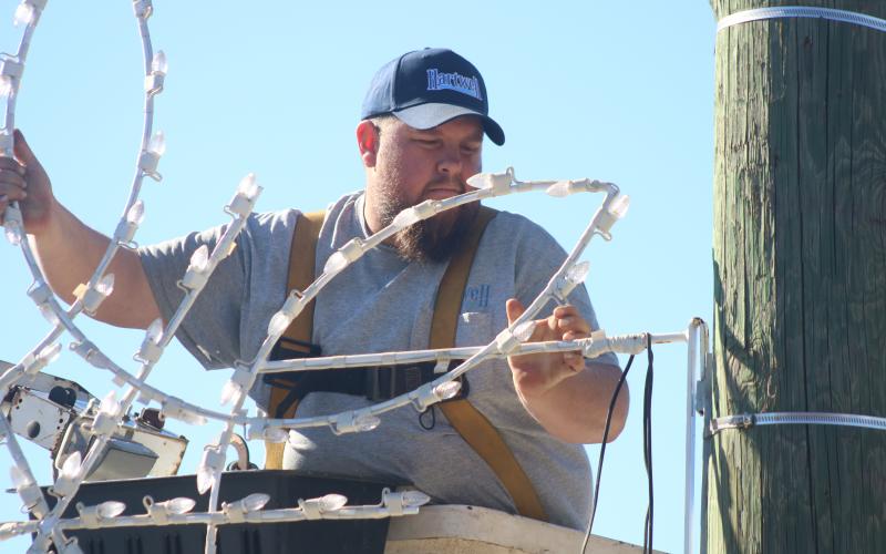 Justin Saylors fixes a lighted snowflake to a utility pole on Depot Street Tuesday afternoon.