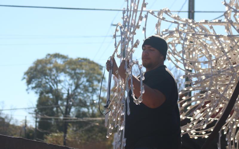 Dante Clark picks up a decoration to hand to Saylors in the bucket truck.