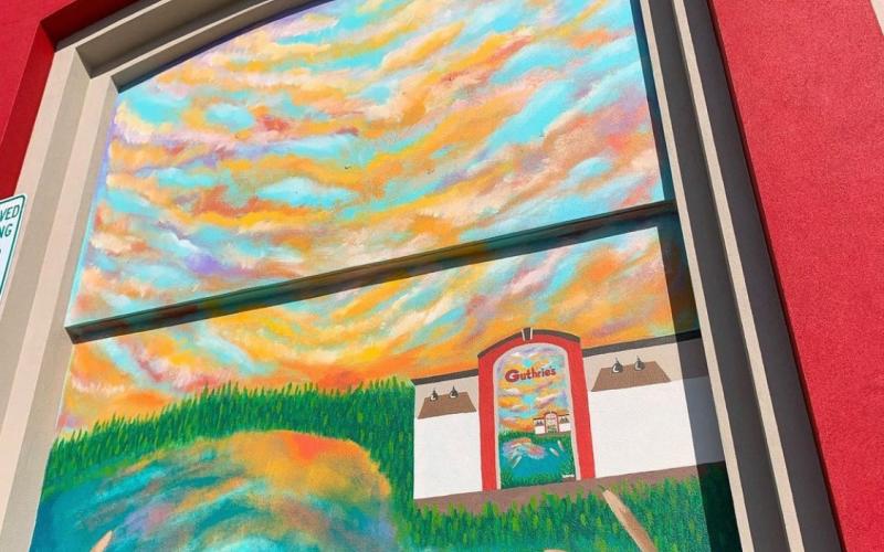 The new Guthrie's building sports a mural of itself during a sunset.