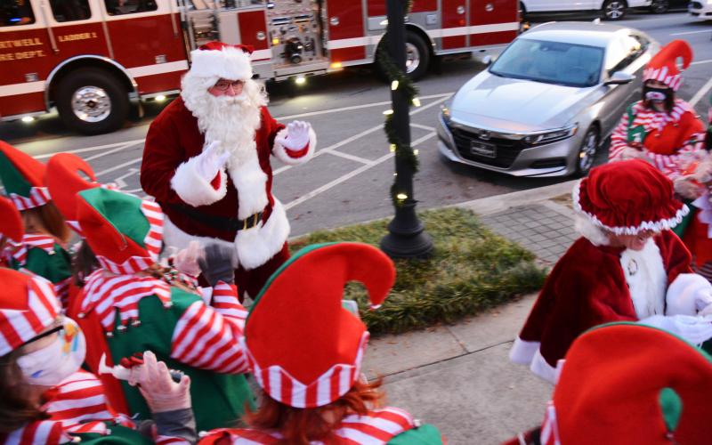 Santa waves to his elves as they greet him and Mrs. Claus, who hitched a ride to the event with the Hartwell Fire Department.