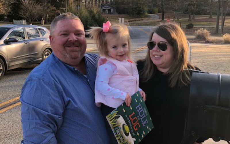 Charlie and Kim Pierce pose for a picture with their daughter, Camille, and a book provided by the Imagination Library.  Photo submitted