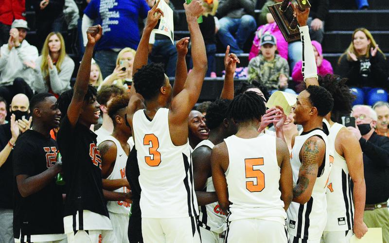 Sunshot by Michael Hall - Hart County senior Shone Webb, right, holds up the Region 8-AAA trophy on Saturday, Feb. 20, at Hart County High School after the Bulldogs defeated Monroe Area 61-52 to claim the school’s first boys’ basketball region championship since 2008.
