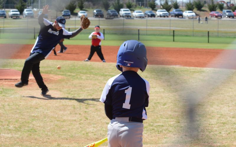Grady Skelton knocks a hit towards his coach who balances on one foot to steer clear of the ball.