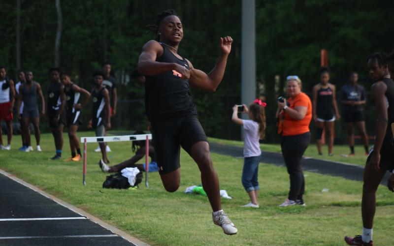 Sunshot by Grayson Williams - Hart County senior Quinn Moore leaps through the air during an event on senior night at Hart County High School.