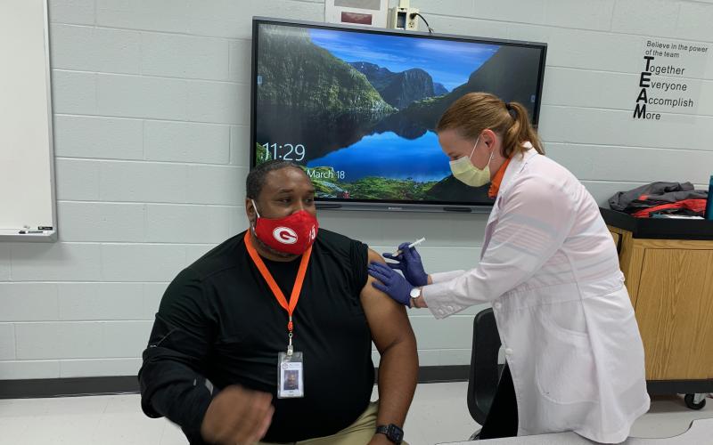 Photo submitted - Ruth Daniel, a volunteer for the Hart County Health Department, right, administers Johnson &amp; Johnson’s COVID-19 vaccine to Hart County Middle School Assistant Principal Earl Fouch, left, during the school system’s vaccine clinic day.