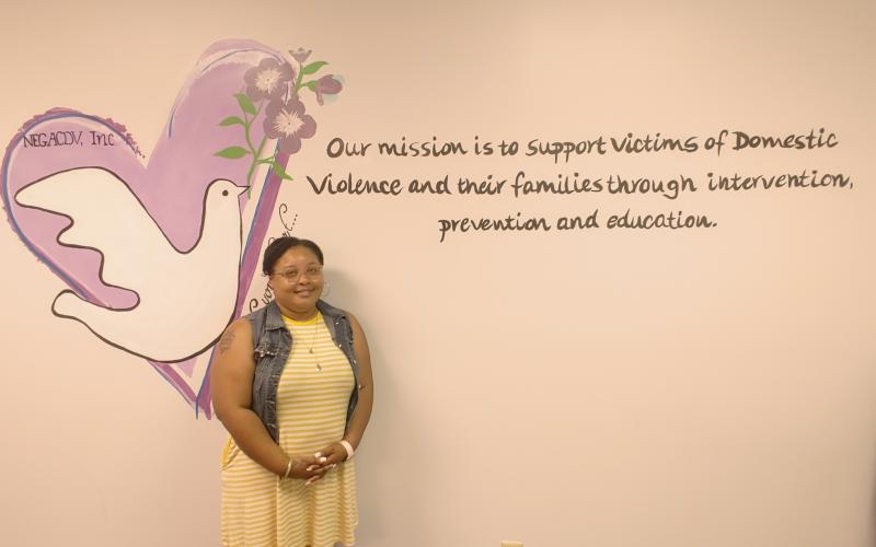 Dan Hunt/The Hartwell Sun - Sequilyous Mclendon, senior care advocate, poses in front of the mission statement at the Northeast Georgia Council on Domestic Violence.