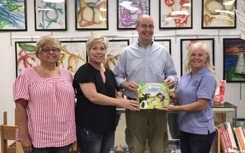 Submitted photo - Hart County Farm Bureau Women’s Committee chair, Patti York, right, Hart County Farm Bureau office manager, Tina Simmons, left, and Angie Brown, Hart EMC, present a copy of the children’s book “Tales of the Dairy Godmother: Chuck’s Ice Cream Wish” to Richard Sanders, who accepts the book for the Hart County Public Library.