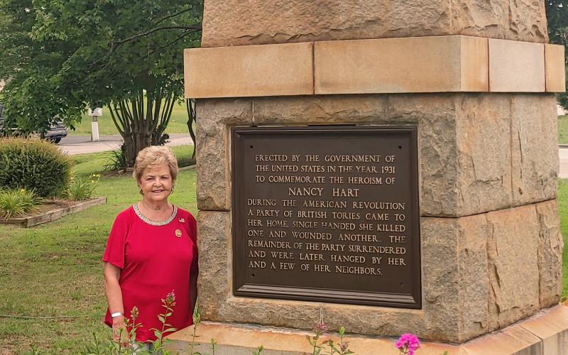 Dan Hunt/The Hartwell Sun Peggy Tucker poses next to the Nancy Hart monument near Old 29 Highway in Hartwell. Tucker helped to procure the monument and plant the adjacent garden.