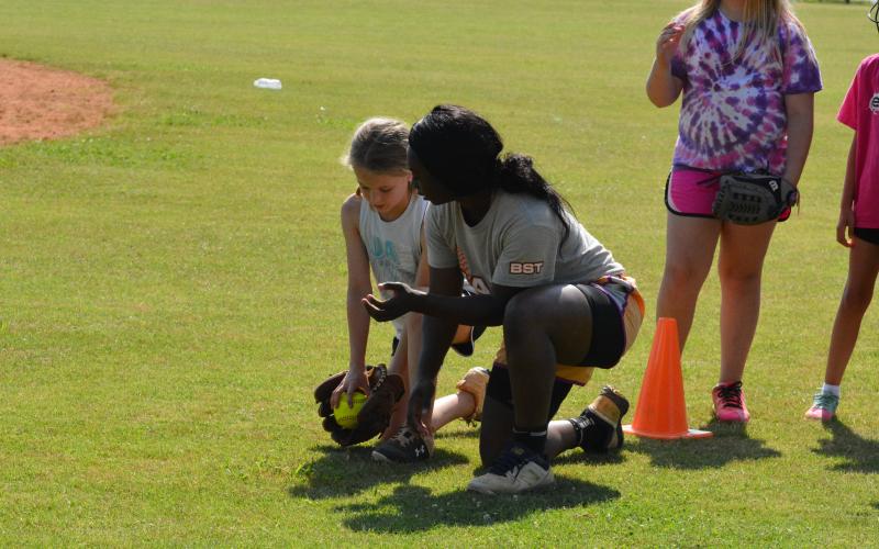 Taikibrea “Red” Campbell helps teach a young camper how to handle a ground ball.