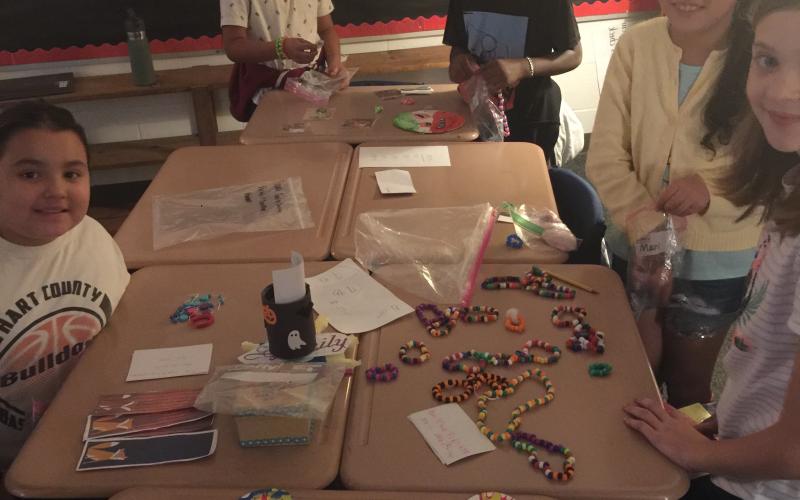From left to right, students Allie Martinez-Johnson, Jaylen Perez-Rangel, Amonzo Gantt, Maria Benites, and Anna Holmes set up their booths for the Economics Fair at South Hart Elementary School.