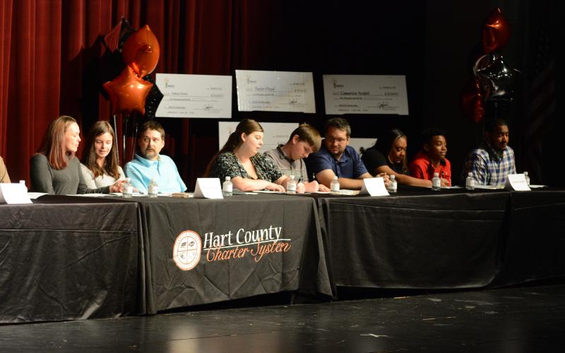 Drew Dotson/The Hartwell Sun From left to right, students Taylor Floyd, Joshua Vaughn and Camarion Verdell sign their scholarships as their proud families look on.