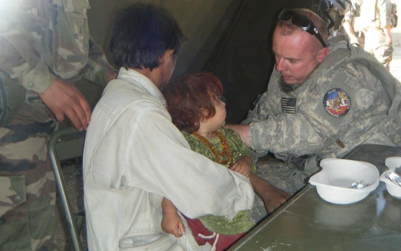 Jason Ford, currently Hartwell’s economic and community development director, treats a child overseas during his time as a medic for our armed forces.