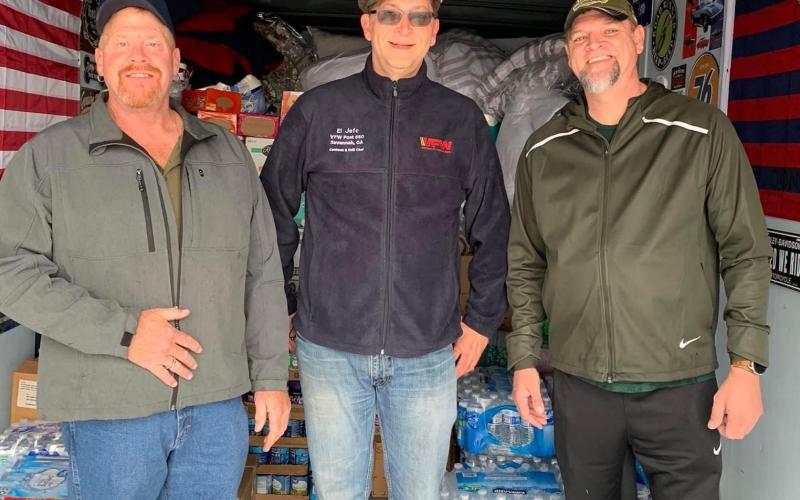 Patrick Wireman (left), a VFW volunteer (center), and Jason Nichols (right) help load supplies in Wireman’s trailer for tornado victims in Ky.
