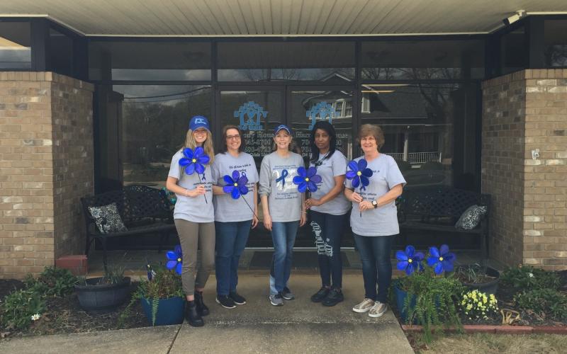From left to right, Andrea Ploussard, Wendy Risner, Laurie Whitworth (CEO), Kimberely Brewer and Sydney Jordan stand outside Harmony House holding blue pinwheels, which is the national symbol for child abuse prevention month. The pinwheel connotes playfulness, joy, and childhood.