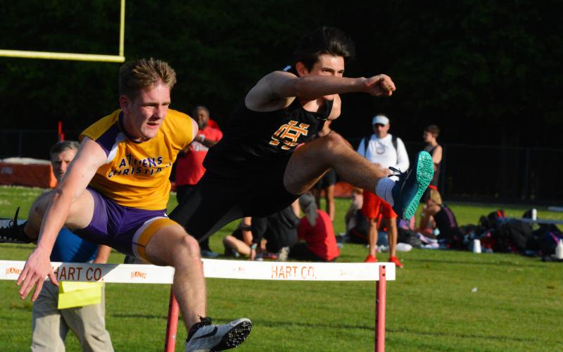Justin Coker leaps a hurdle, Superman-style, in the 110-meter hurdles race.