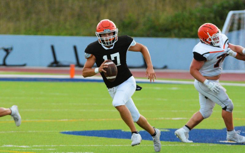 Austen Whitworth scrambles out of the pocket, looking downfield.