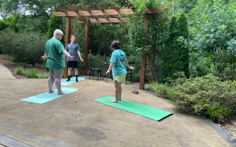 Yoga instructor Briana Kay (right) leads Jake Mitchell (left) and Justin Temples (center) in a yoga session at the Hart County Botanical Garden pavillion.