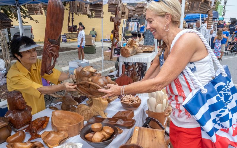 Sherry Wheeler (right) is seen purchasing a wood carving from Deresa Dela Cruz’s booth during the Pre-Fourth Festival.