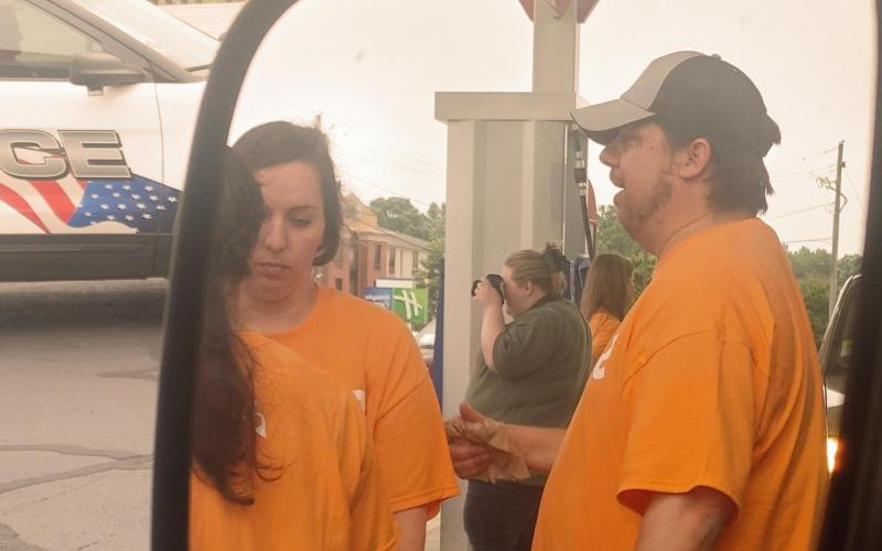 Dan Hunt/The Hartwell Sun Sideview mirror shot of three volunteers from The Pointe Church pumping gas and volunteering time and money in Lavonia on May 26.