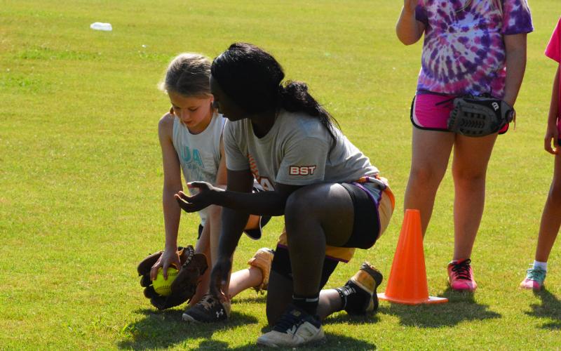 Taikibrea “Red” Campbell helps teach a young camper how to handle a ground ball.