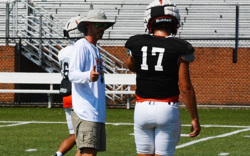 Caleb Sorrells coaches up quarterback Austen Whitworth at practice.