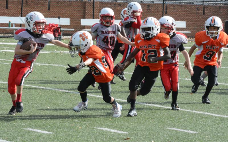 Hart County 7U running back Tristan Gray throws a stiff arm with defender Emmett Wise bearing down.